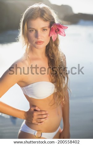 Beautiful blonde with flower hair accessory on the beach on a sunny day