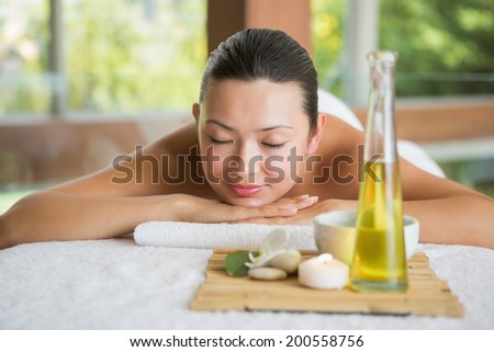Brunette lying on massage table with tray of beauty treatments at the health spa
