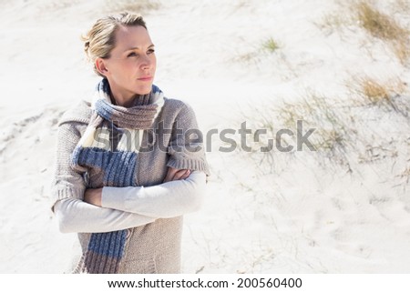 Attractive blonde standing on the beach in woolen scarf on a bright but cool day