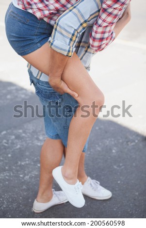 Man giving his girlfriend a piggy back on a sunny day in the city