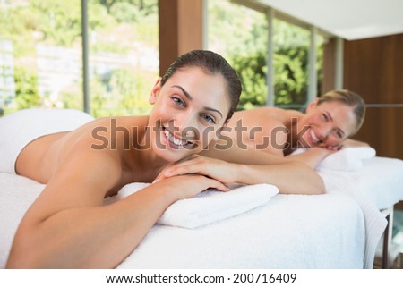 Smiling friends lying on massage tables in the health spa
