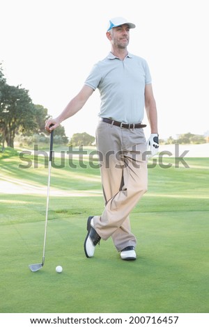 Handsome golfer standing with club on a sunny day at the golf course