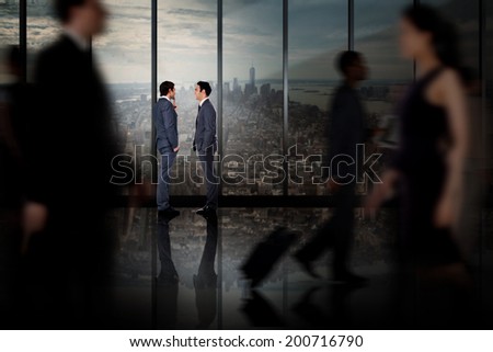 Businessmen talking against room with large window looking on city