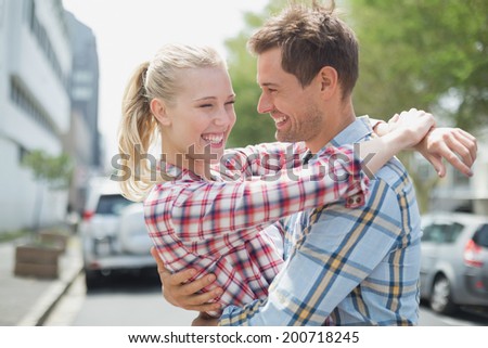 Couple in check shirts and denim hugging each other on a sunny day in the city
