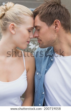 Hip young couple sitting on steps smiling at each other on a sunny day in the city