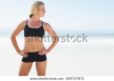 Fit blonde standing on the beach on a sunny day