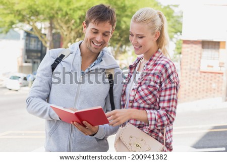 Young tourist couple consulting the guide book on a sunny day in the city