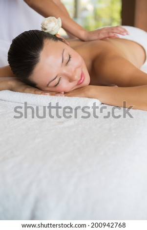 Brunette enjoying a peaceful massage with eyes closed at the health spa