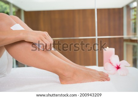 Woman waxing her legs herself in the health spa