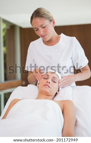 Peaceful brunette getting facial massage from beauty therapist in the health spa