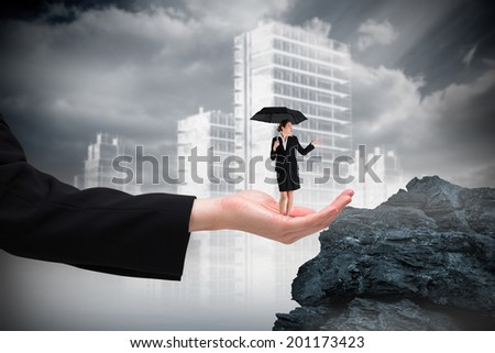Young businesswoman holding umbrella in hand against large rock overlooking outline of city