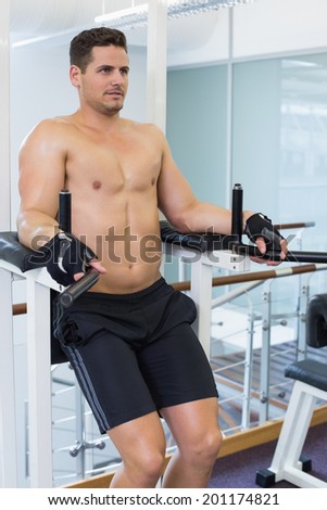 Shirtless bodybuilder doing leg lifts at the gym