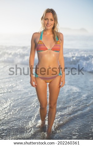 Happy blonde standing by the sea posing in bikini on a sunny day