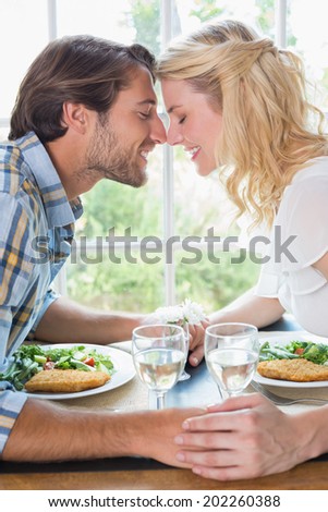 Cute affectionate couple having a meal together at home in the dining room
