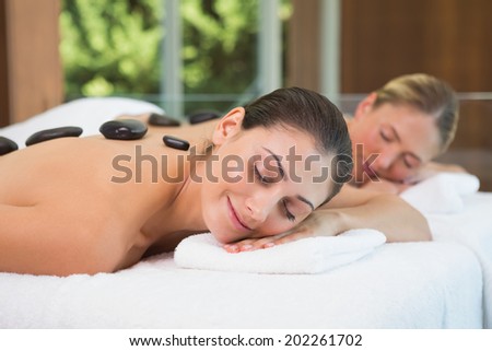 Pretty friends getting hot stone massages together in the health spa