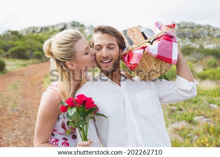 Cute couple going for a picnic with woman kissing boyfriends cheek on a sunny day Cute couple going for a picnic with woman kissing boyfriends cheek on a sunny day