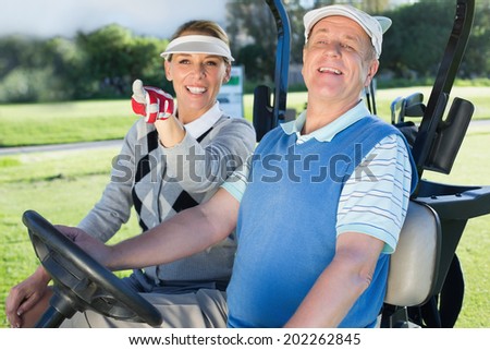 Happy golfing couple sitting in golf buggy looking around on a sunny day at the golf course