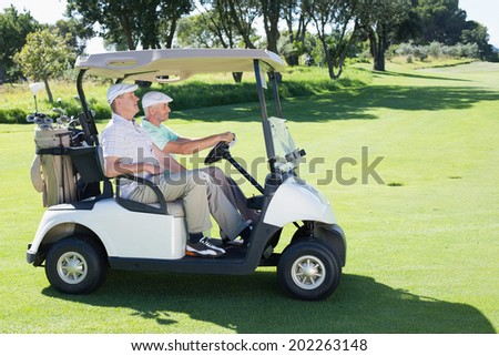 Golfing friends driving in their golf buggy on a sunny day at the golf course