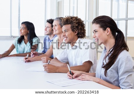 Casual business team taking notes in meeting in the office