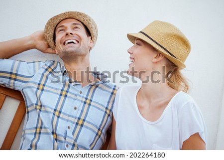 Young hip couple laughing on bench on a sunny day in the city