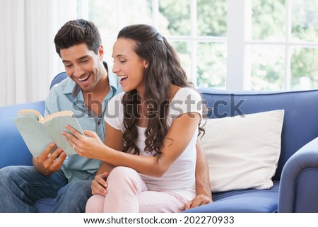 Attractive couple reading book on the sofa at home in living room
