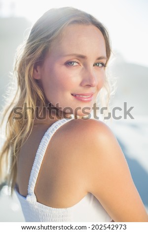 Pretty blonde standing at the beach in white sundress on a sunny day