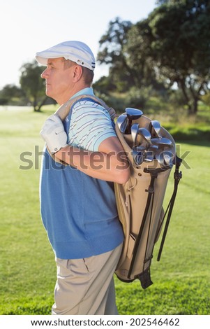 Golfer standing holding his golf bag on a sunny day at the golf course