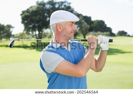 Golfer standing and swinging his club on a sunny day at the golf course