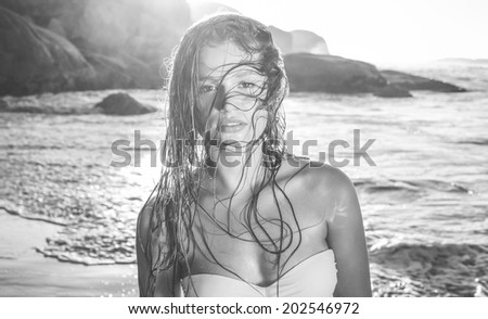 Beautiful blonde in white bikini at the beach with wet hair in black and white