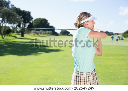 Lady golfer teeing off for the day on a sunny day at the golf course