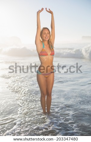 Happy blonde standing in the sea posing in bikini on a sunny day