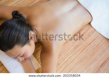 Content brunette relaxing on massage table at the health spa