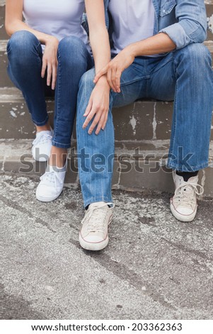 Hip young couple in denim sitting on steps on a sunny day in the city