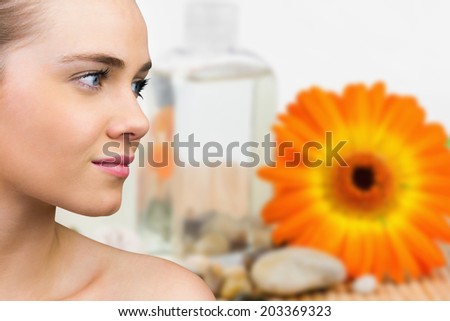 Smiling blonde natural beauty against flower with beauty products