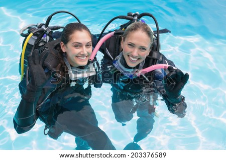 Smiling friends on scuba training in swimming pool making ok sign on a sunny day