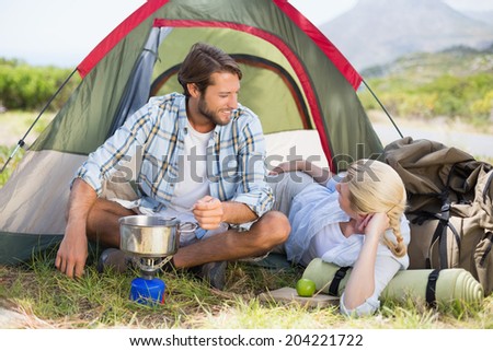 Attractive happy couple cooking on camping stove on a sunny day