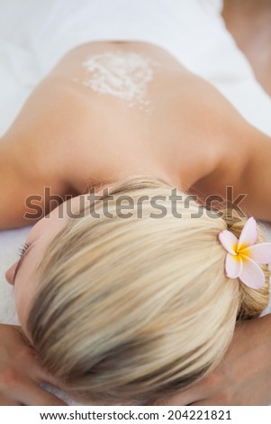 Beautiful blonde lying on massage table with salt scrub treatment at the health spa