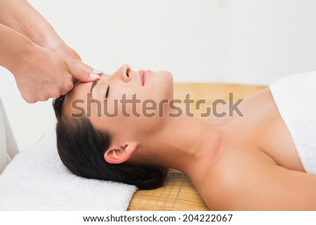 Smiling brunette enjoying a head massage in the health spa