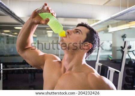 Close-up of a sporty young man drinking energy drink in gym
