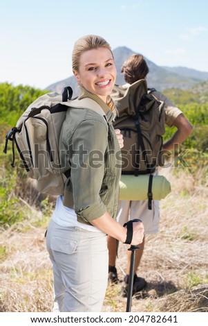 Attractive hiking couple walking on mountain trail woman smiling at camera on a sunny day