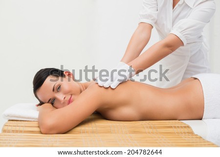 Beautiful brunette enjoying an exfoliating back massage in the health spa