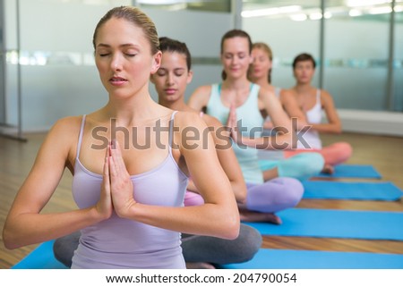 Yoga class in lotus pose in fitness studio at the leisure center