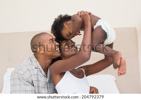 Happy couple on bed with baby daughter at home in the bedroom