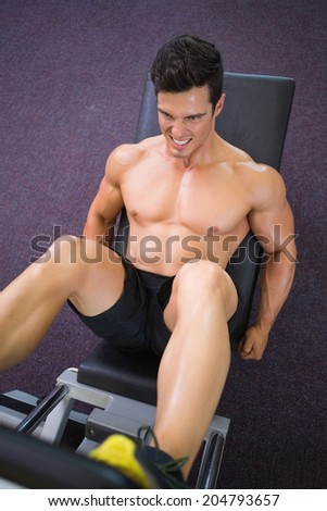 High angle view of male weightlifter doing leg presses in gym