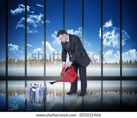 Mature businessman watering tiny business team against room with large window looking on city skyline