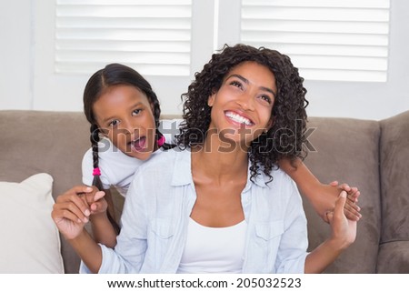 Pretty mother sitting on the couch with her daughter at home in the living room