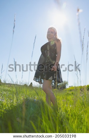 Pretty blonde in sundress smiling at camera on a sunny day in the countryside