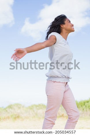 Casual pretty woman standing with arms out on a sunny day in the countryside
