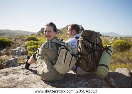 Hiking couple sitting on mountain terrain on a sunny day