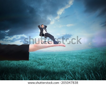 Businessman relaxing in swivel chair against blue sky over green field